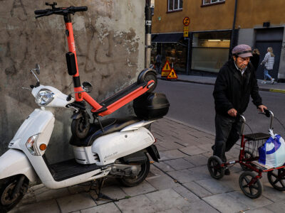 Felparkerad elscooter &auml;ldre man med rullator