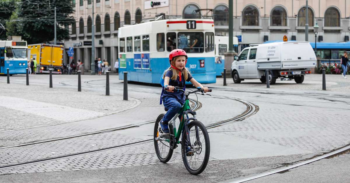 En flicka cyklar &ouml;ver sp&aring;rv&auml;gssp&aring;r. I bakgrunden en sp&aring;rvagn