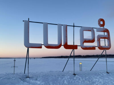 Skylt med bokst&auml;verna LULE&Aring; framf&ouml;r isen en vacker vinterkv&auml;ll med skymning. Gr&ouml;n omst&auml;llning i norra Sverige
