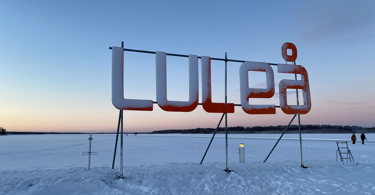 Skylt med bokst&auml;verna LULE&Aring; framf&ouml;r isen en vacker vinterkv&auml;ll med skymning. Gr&ouml;n omst&auml;llning i norra Sverige