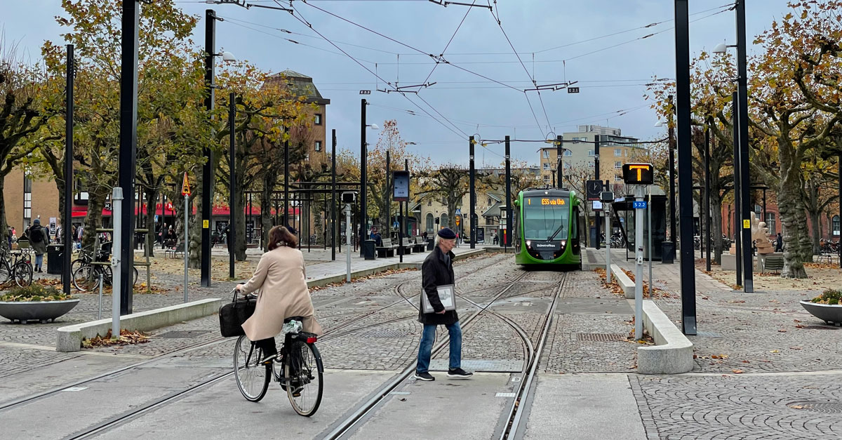 En cyklist och en fotg&auml;ngare passerar sp&aring;ren f&ouml;r Lunds sp&aring;rv&auml;g.