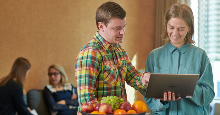 Tv&aring; medarbetare tittar p&aring; en laptop och diskuterar.