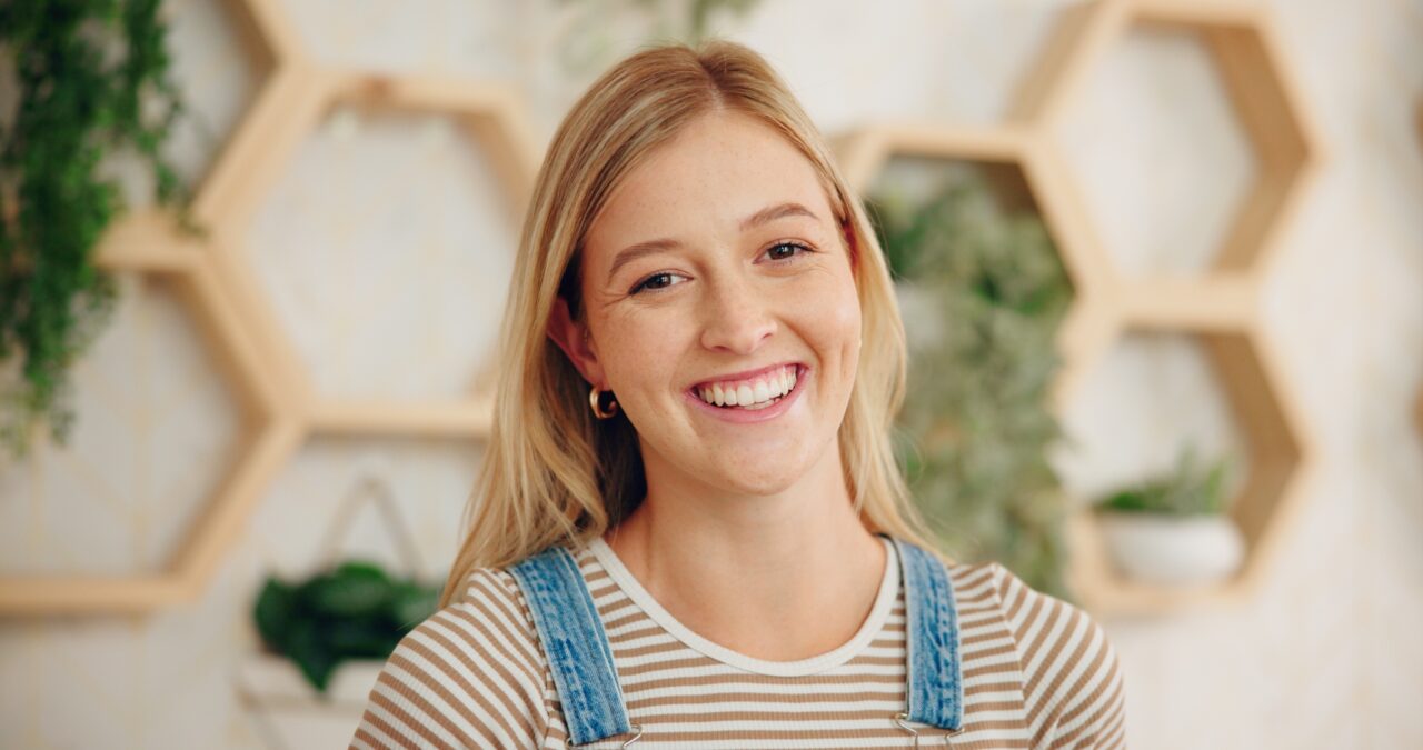 glad tjej i snickarbyxor med gr&ouml;na v&auml;xter i bakgrunden